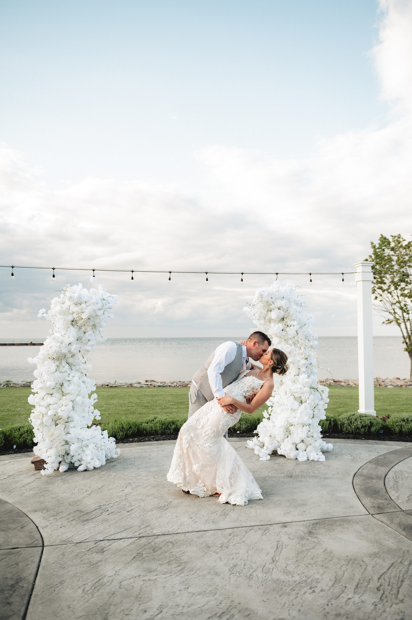 couple in wedding attire kissing in front of water